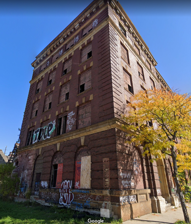 Warner Swasey building exterior facade with graffiti coverage and boarded windows. 