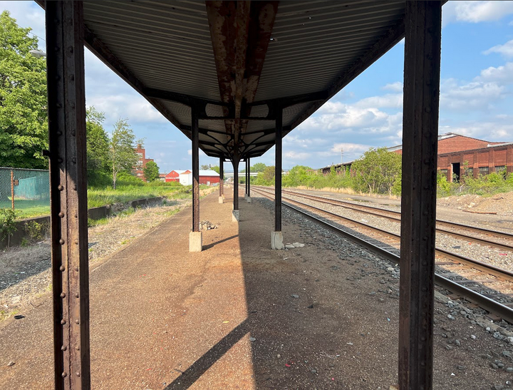 View of Train station near dusk with double tracked rail to the right and abandoned right of way on left. 